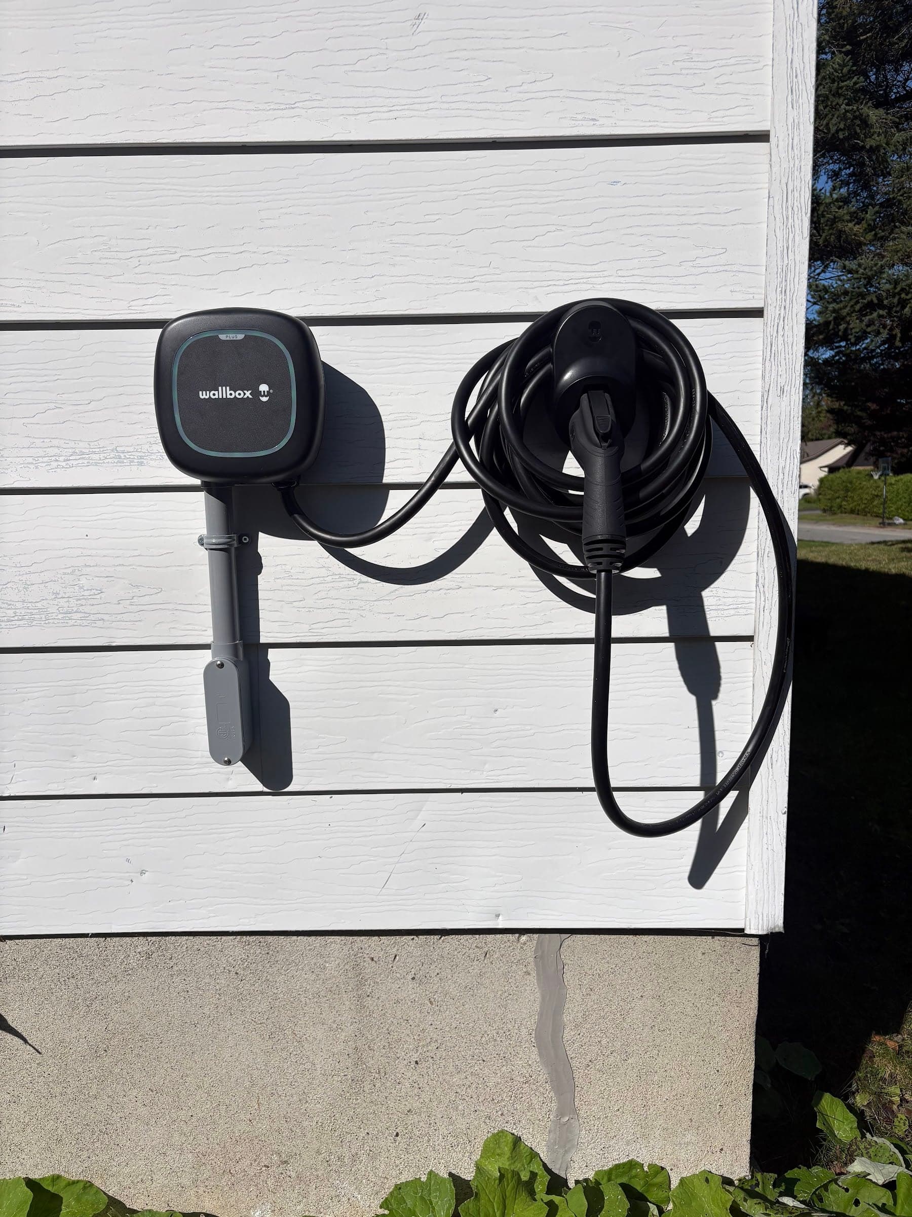 Borne de recharge Wallbox installée sur un mur extérieur, câble enroulé