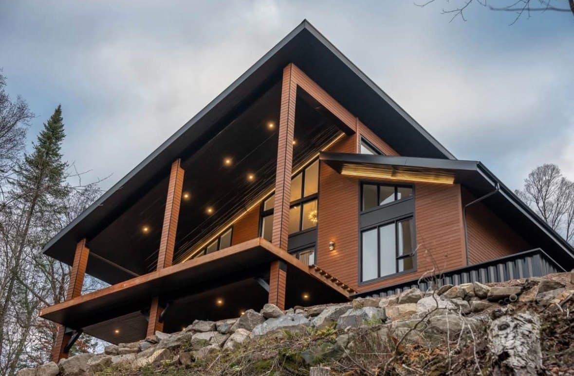 Chalet moderne illuminé par des luminaires encastrés dans le soffite, à la tombée du jour